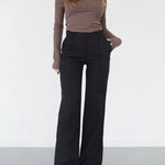 Woman wearing high-waisted black wide-leg trousers with a ribbed brown top and white sneakers
